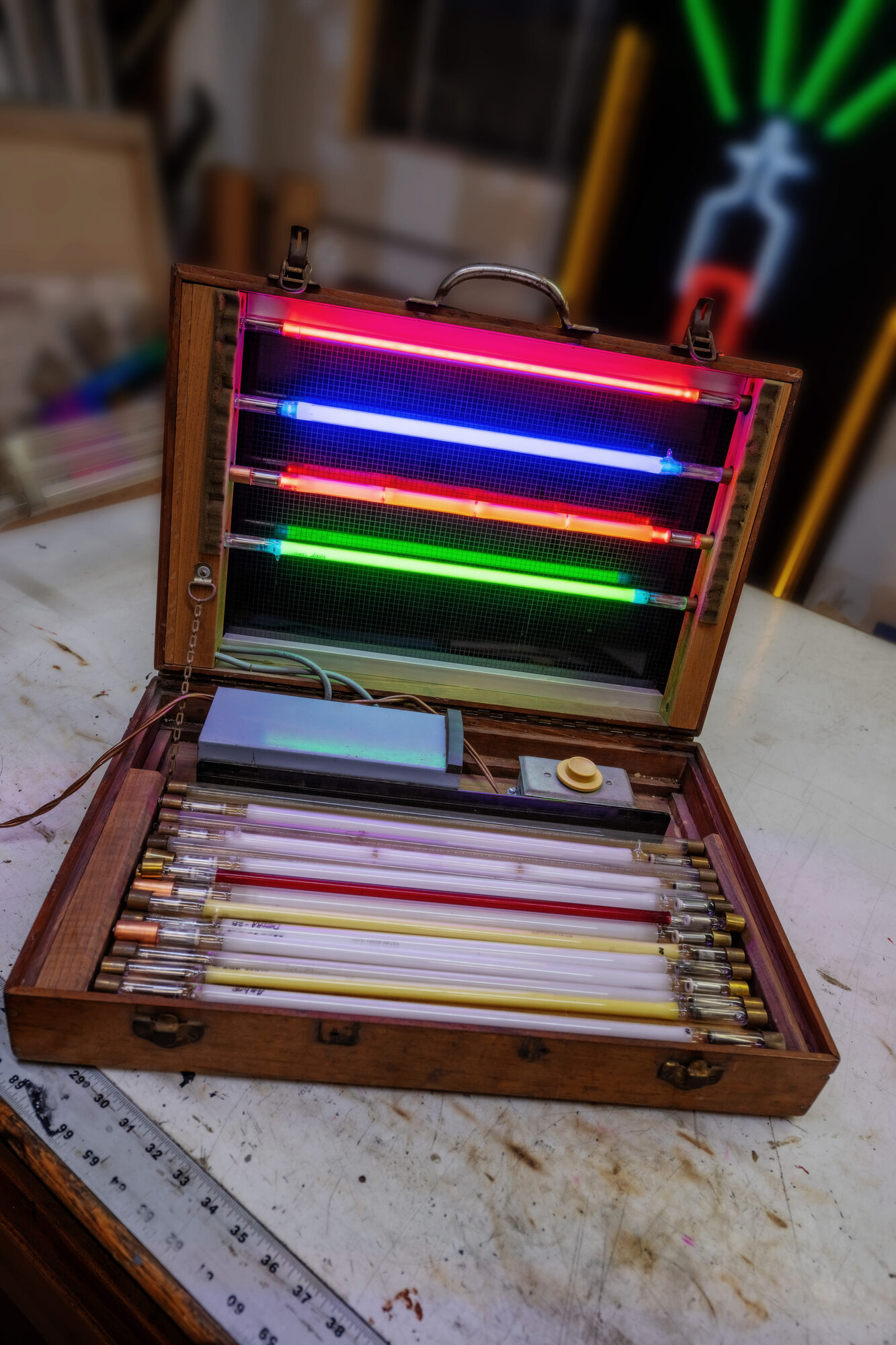 Hand-bent neon tubes in a case on a workbench, from the studio of Larry Simmons and Tony Greer